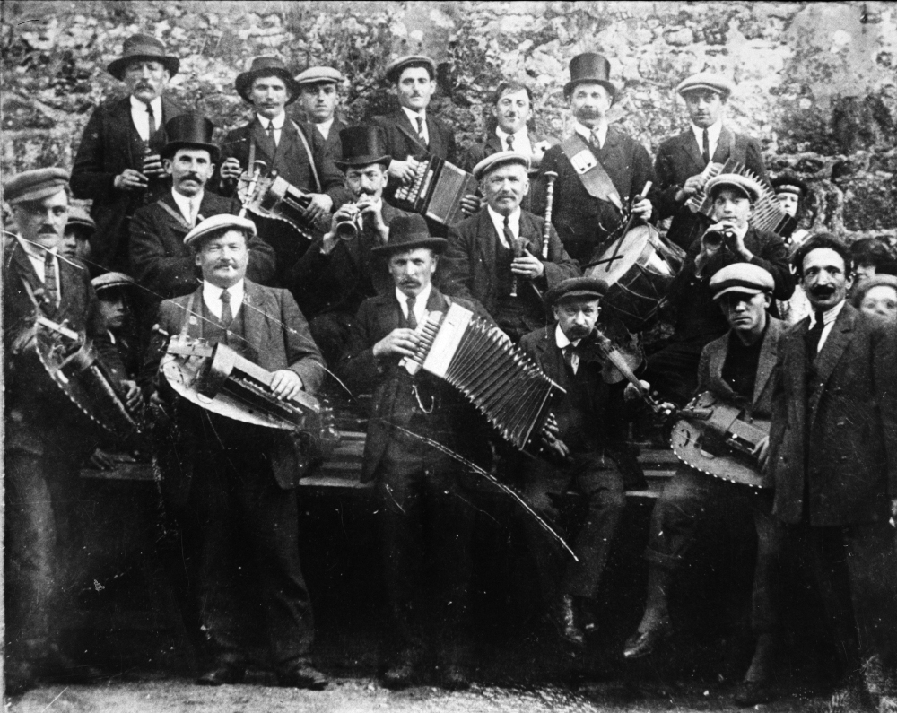 Le concours de Moncontour en 1925 : les principales pratiques instrumentales traditionnelles  en Bretagne y sont représentées, hormis la veuze !  Coll. Collectif Vielle en Bretagne – la Bouèze, Dastum.<br><br>Concours de musique au quartier de l'embranchement à Moncontour en 1925.<br>De haut en bas et de gauche à droite : premier rang M. Mauvillo de Hénon (bombarde), Yves Agat de Ploeuc (vielle) François Pellan de Hénon (accordéon), M. Hamono de Bréhand (accordéon), M. Le Collonier de Hénon (accordéon), M. Couderc de Moncontour (tambour), M. Thébaud de Plémy (accordéon) Deuxième rang Gilbert Hugues de Plouguenast (biniou), Yves Bosher de Gausson (bombarde), M. Lefèbvre père de La Motte (biniou), M. Lefbvre fils (bombarde) Troisième rang Pierre Ecobichon de Hénon (vielle), François Le Borgne de Hénon (vielle) M. Caro de Plémy (accordéon), Pierre Ruellan de Moncontour (violon), Xavier Thomas de Moncontour (vielle) M. Guigo du Comité des fêtes. Premier prix biniou bombarde tambour : Hugues Boscher Couderc 1er prix vielle Le Borgne.