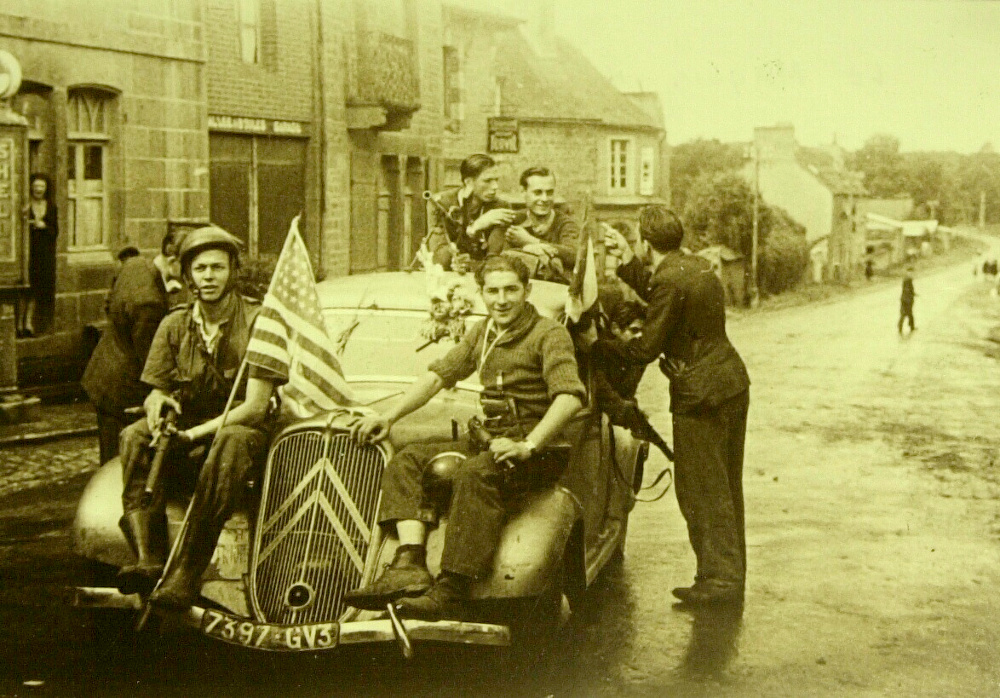 À Merdrignac (Côtes-du-Nord), le jeudi 3 août 1944, le maquis de Creneleu sort de la clandestinité. Image emblématique de la Libération de la Bretagne, des FFI armés de sten parachutées par les Alliés et circulant à bord d'une traction avant Citroën sans doute réquisitionnée, posent pour la photo à Merdrignac. À partir du 6 juin, les maquisards ont été nombreux dans le Centre-Bretagne - Collection du Musée de Saint-Marcel. Photo Yves Moisan - DR